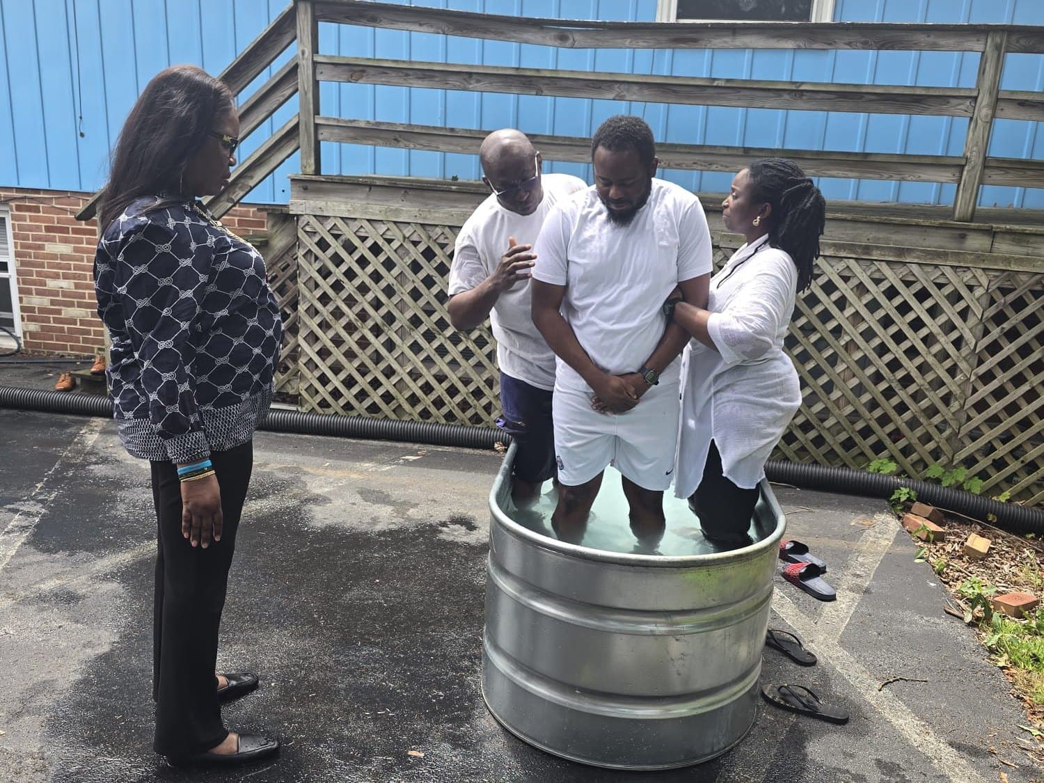 A new believer praying in the baptism waters with Pastor Dr. Kina and the baptism team